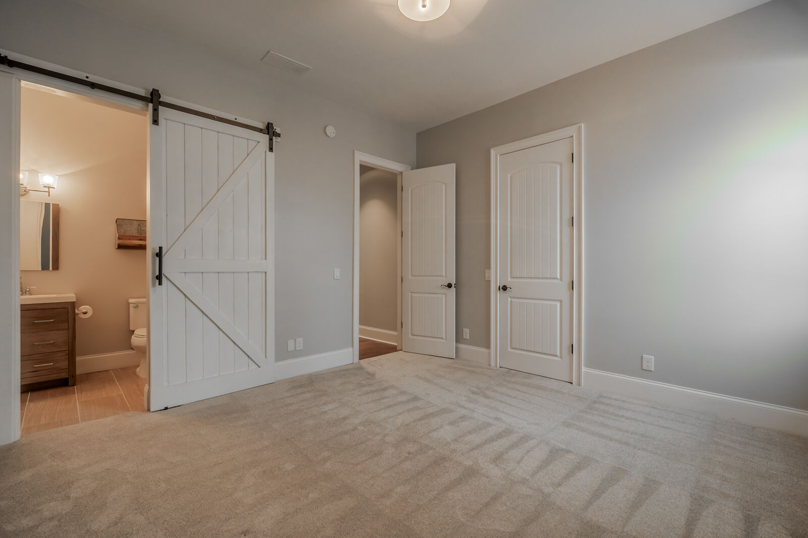 Guest bedroom with a sliding barn door to its private bath